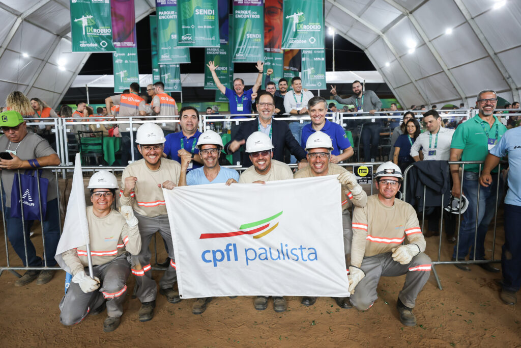 Equipe reunida com uma bandeira da CPFL Paulista